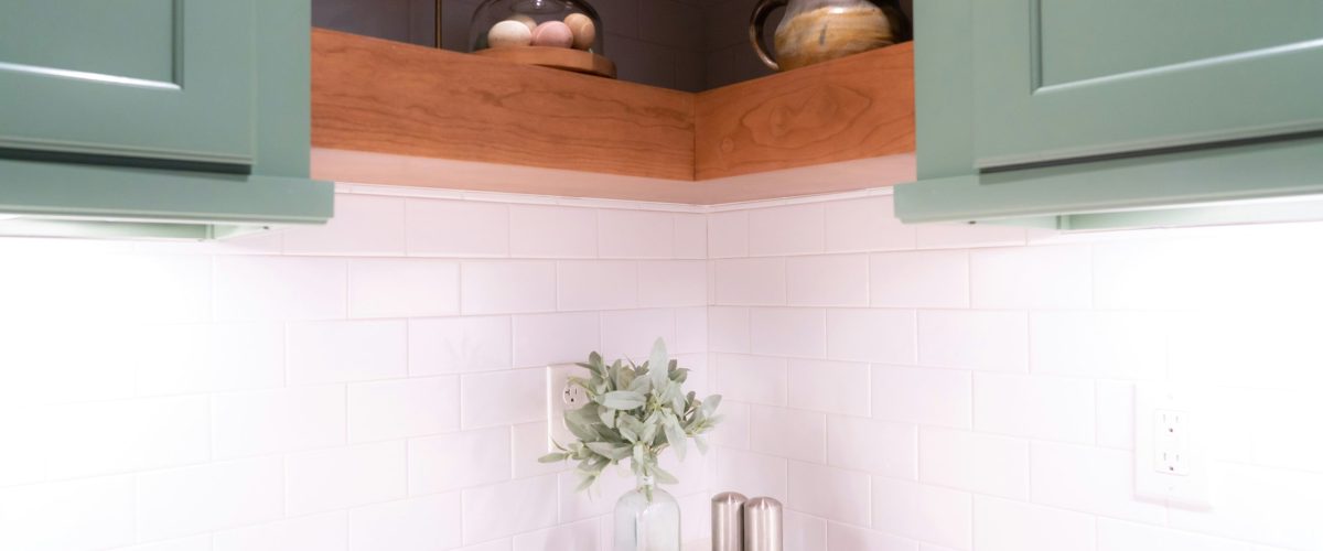Open-doors “reveal” photo of oak cabinet fronts with a concealed pantry swung open, showing organized shelves with labeled bins and LED strip lighting. Shot straight-on at counter height, soft daylight, natural colors.Hidden Pantry Behind Kitchen Cabinets
